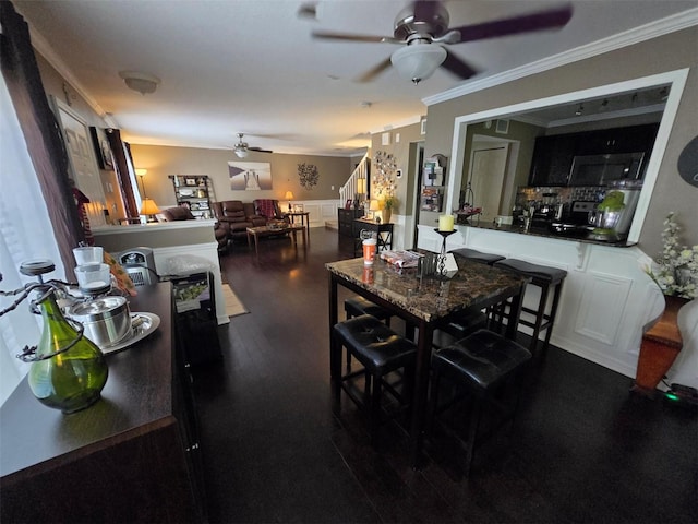 dining space featuring dark hardwood / wood-style flooring, crown molding, and ceiling fan