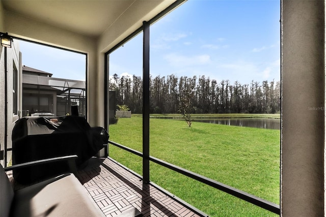 sunroom featuring a water view