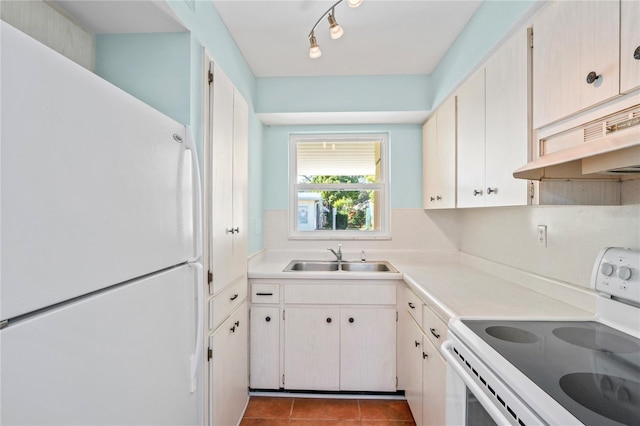 kitchen featuring light tile patterned floors, white appliances, white cabinetry, and sink