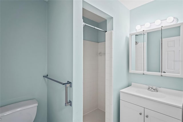 bathroom featuring tiled shower, vanity, and toilet