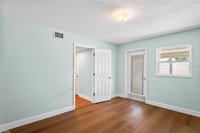 unfurnished room with a textured ceiling and hardwood / wood-style flooring