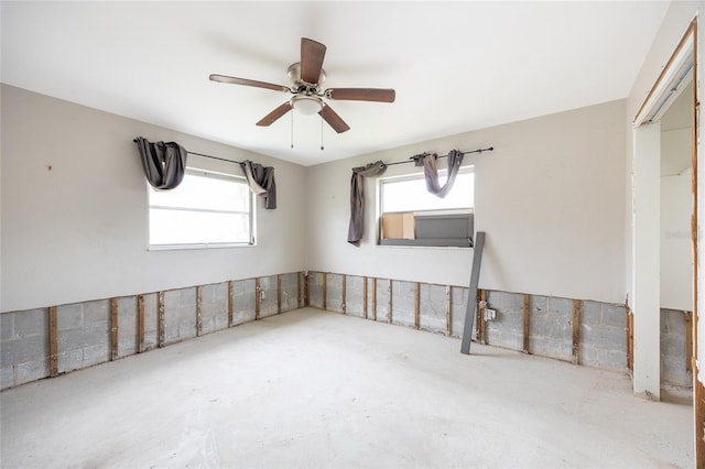 unfurnished room with ceiling fan and concrete flooring