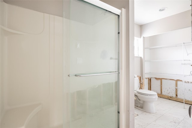 bathroom featuring toilet and a shower with shower door