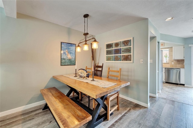 dining room with wood-type flooring and a textured ceiling