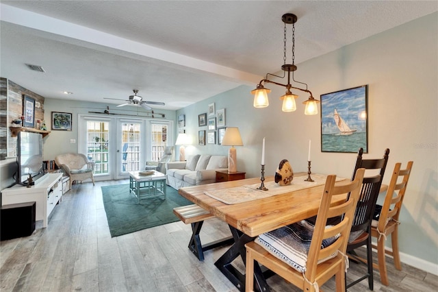 dining room with beam ceiling, ceiling fan, wood-type flooring, and a textured ceiling