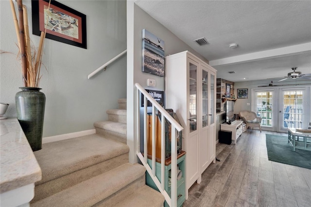 stairs featuring ceiling fan, wood-type flooring, a textured ceiling, and french doors