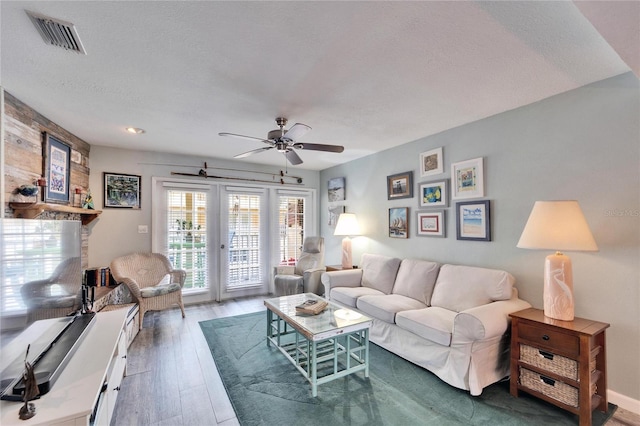 living area featuring visible vents, wood finished floors, a textured ceiling, french doors, and a ceiling fan