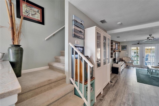 stairway featuring visible vents, wood finished floors, baseboards, a textured ceiling, and french doors