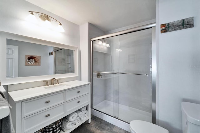 full bath with toilet, a shower stall, wood finished floors, and vanity