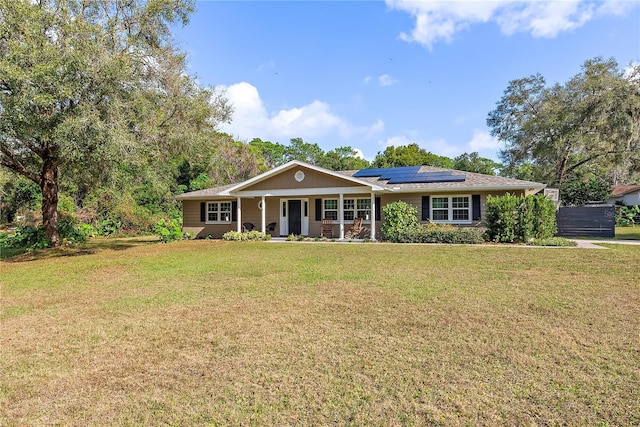 ranch-style home with solar panels, a porch, and a front lawn