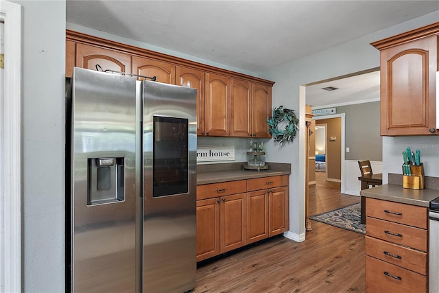 kitchen with dark countertops, visible vents, stainless steel refrigerator with ice dispenser, and wood finished floors