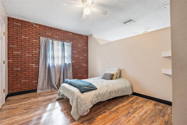 bedroom with visible vents, a textured ceiling, and wood finished floors