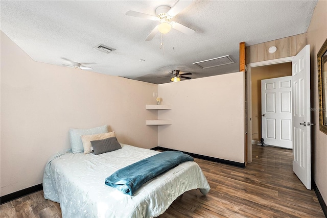 bedroom with attic access, visible vents, a ceiling fan, dark wood-type flooring, and a textured ceiling