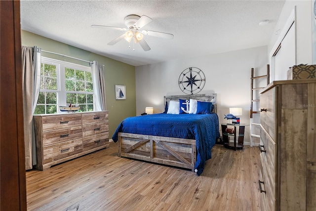 bedroom featuring light wood-style floors, a textured ceiling, and a ceiling fan