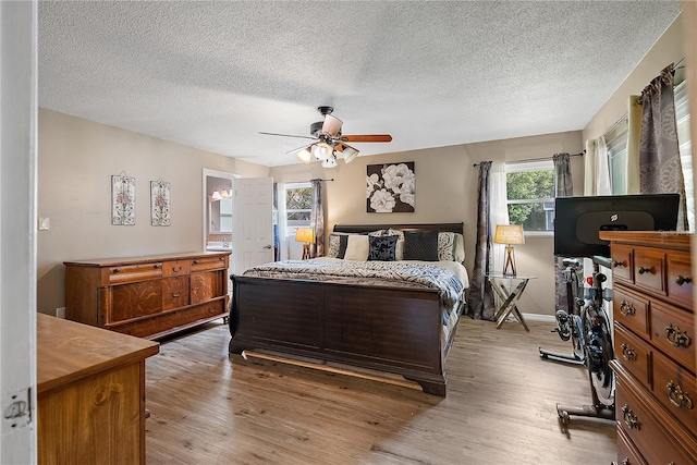 bedroom featuring a textured ceiling, light wood-type flooring, a ceiling fan, and baseboards