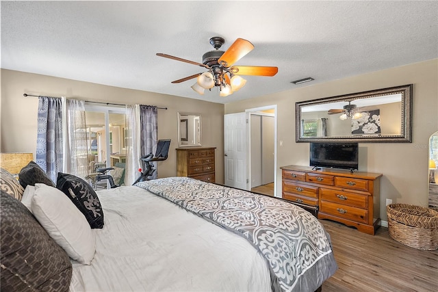 bedroom featuring a textured ceiling, wood finished floors, visible vents, and a ceiling fan