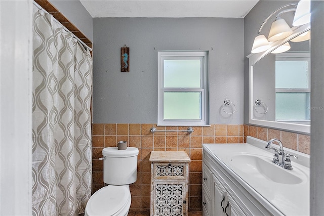 full bath featuring toilet, wainscoting, tile walls, and vanity