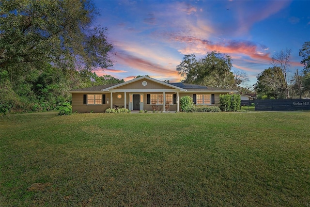 view of front facade with a porch, a front yard, and fence