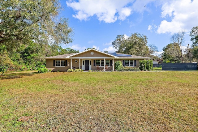 single story home with solar panels, a porch, a front lawn, and fence