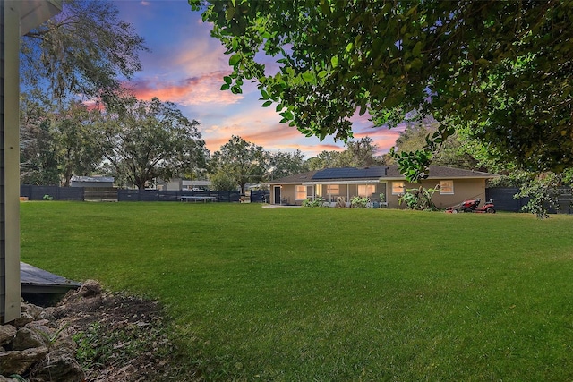 yard at dusk featuring a fenced backyard