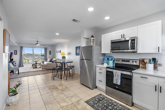 kitchen featuring appliances with stainless steel finishes, light tile patterned floors, white cabinetry, and ceiling fan