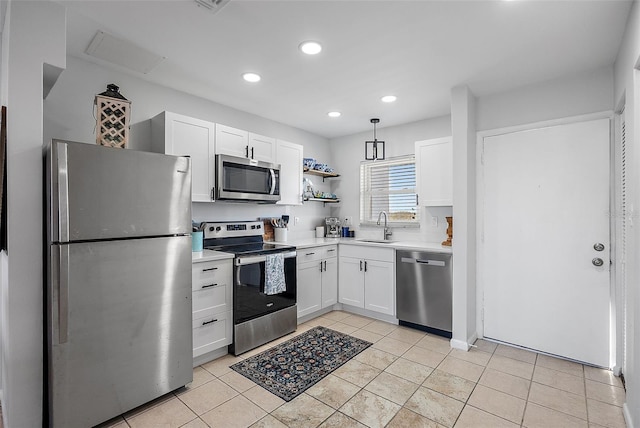 kitchen with hanging light fixtures, sink, light tile patterned floors, appliances with stainless steel finishes, and white cabinetry