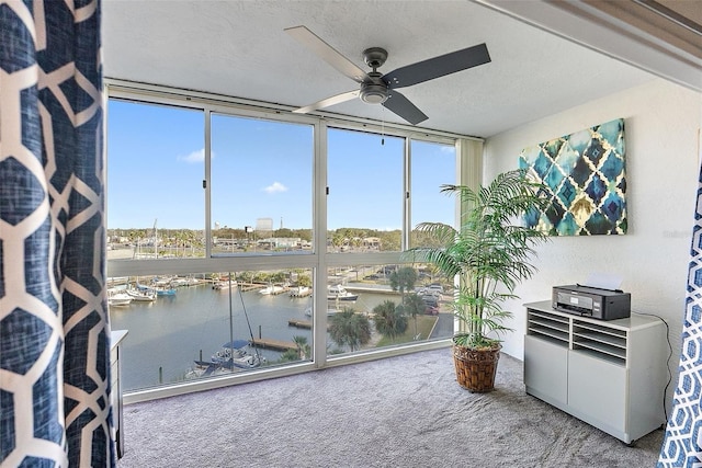 sunroom / solarium with ceiling fan and a water view