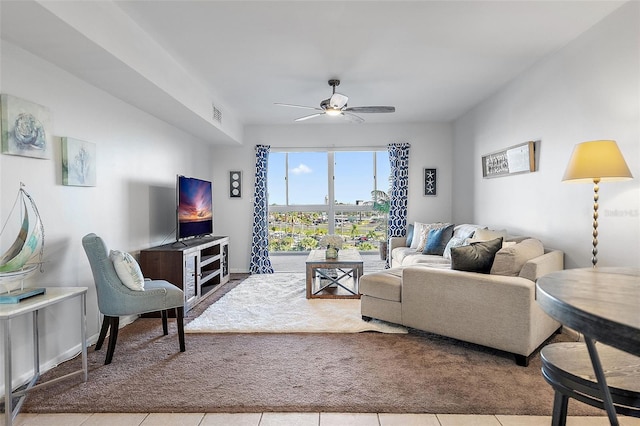 carpeted living area with baseboards, visible vents, a ceiling fan, and tile patterned floors