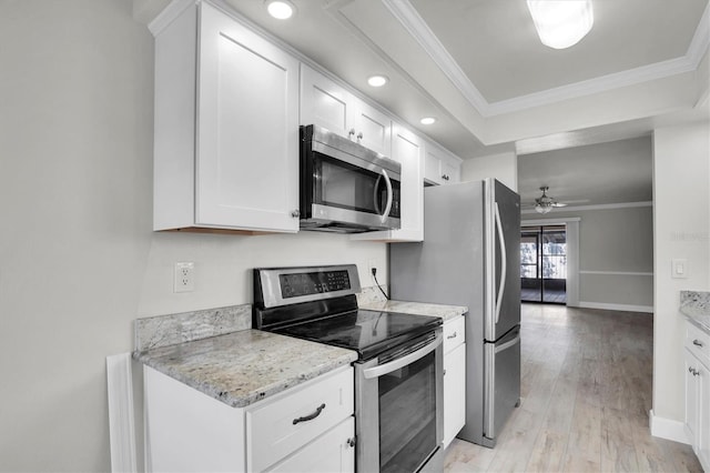 kitchen with light stone countertops, white cabinetry, ceiling fan, stainless steel appliances, and ornamental molding