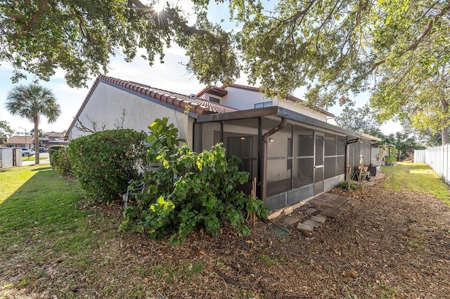 back of property with a sunroom and a lawn