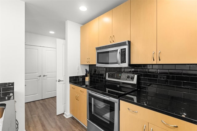 kitchen with tasteful backsplash, dark stone counters, stainless steel appliances, light brown cabinets, and dark hardwood / wood-style floors