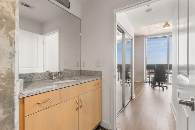 bathroom featuring ceiling fan, vanity, wood-type flooring, and a wall of windows