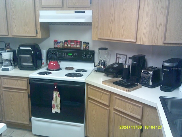 kitchen with range with electric stovetop, light brown cabinetry, sink, and light tile patterned floors