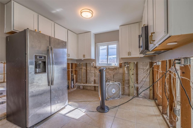 kitchen featuring stainless steel fridge, light tile patterned floors, and white cabinetry