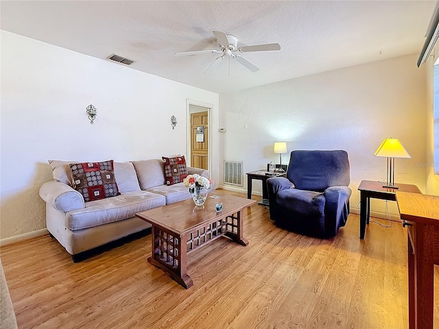 living room with ceiling fan, light hardwood / wood-style floors, and a textured ceiling