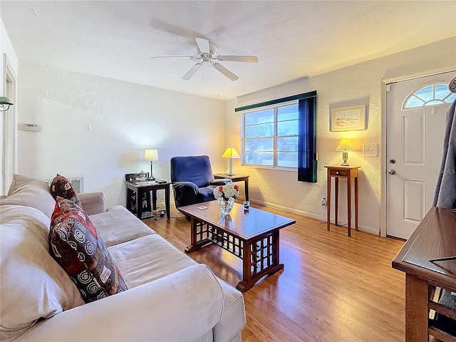 living room with a textured ceiling, light hardwood / wood-style flooring, and ceiling fan