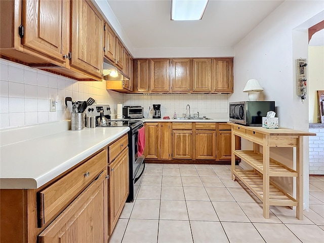 kitchen featuring appliances with stainless steel finishes, sink, light tile patterned floors, and decorative backsplash