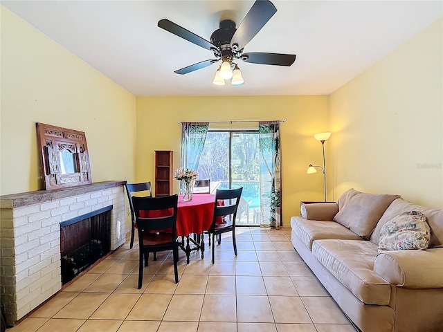 tiled dining room featuring ceiling fan and a fireplace