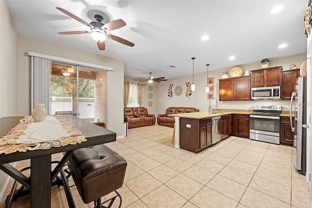 kitchen with sink, hanging light fixtures, kitchen peninsula, light tile patterned floors, and appliances with stainless steel finishes