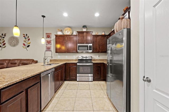 kitchen with appliances with stainless steel finishes, light stone counters, sink, pendant lighting, and light tile patterned flooring