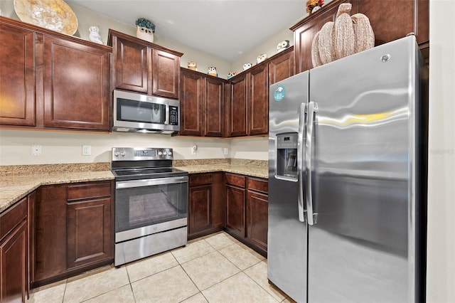 kitchen with dark brown cabinets, light stone counters, light tile patterned floors, and stainless steel appliances