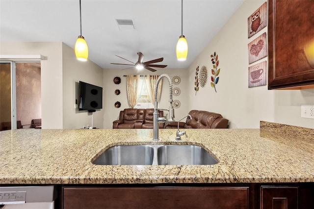 kitchen with white dishwasher, light stone counters, hanging light fixtures, and sink