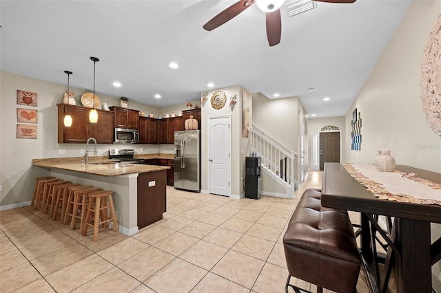 kitchen with kitchen peninsula, stainless steel appliances, ceiling fan, sink, and decorative light fixtures