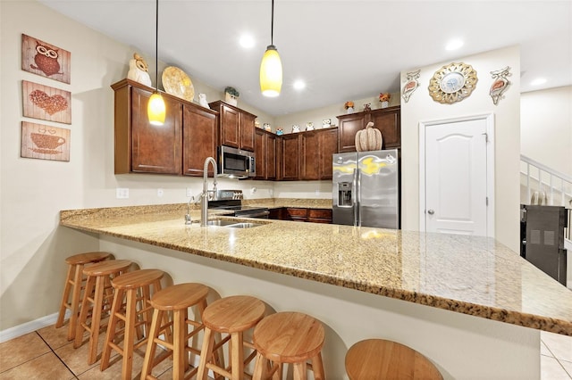 kitchen with kitchen peninsula, appliances with stainless steel finishes, sink, pendant lighting, and light tile patterned flooring