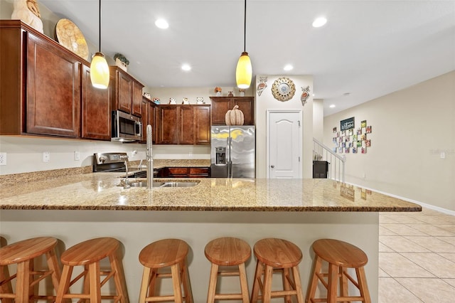 kitchen featuring a kitchen breakfast bar, light stone counters, pendant lighting, light tile patterned floors, and appliances with stainless steel finishes