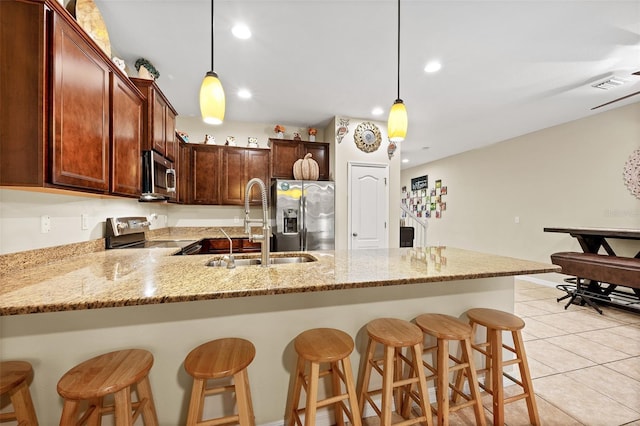 kitchen with stainless steel appliances, sink, pendant lighting, a breakfast bar area, and light tile patterned flooring