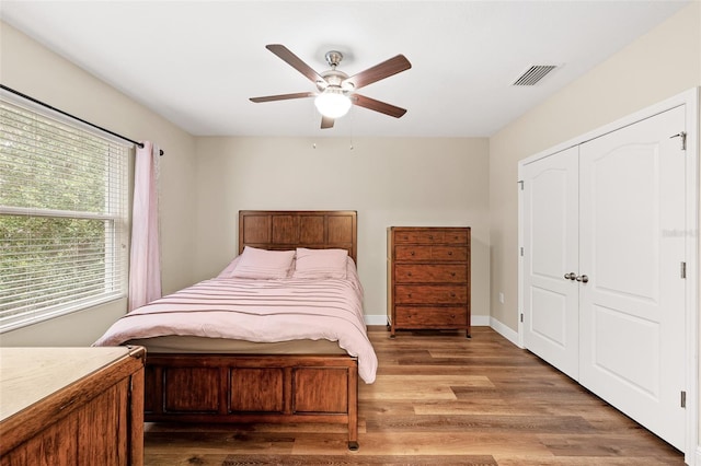 bedroom with a closet, light hardwood / wood-style flooring, and ceiling fan