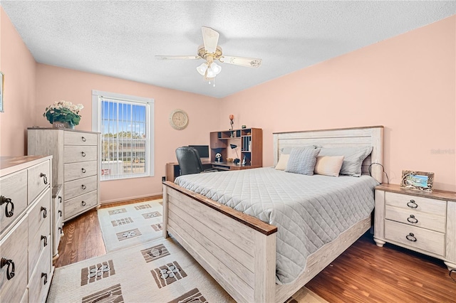 bedroom with ceiling fan, dark hardwood / wood-style flooring, and a textured ceiling