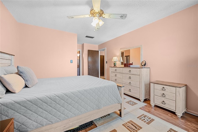 bedroom featuring ceiling fan, light hardwood / wood-style floors, and a textured ceiling