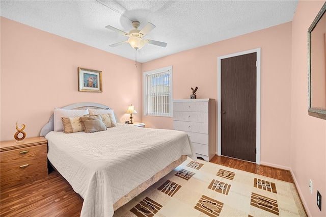 bedroom featuring ceiling fan, a textured ceiling, and hardwood / wood-style flooring